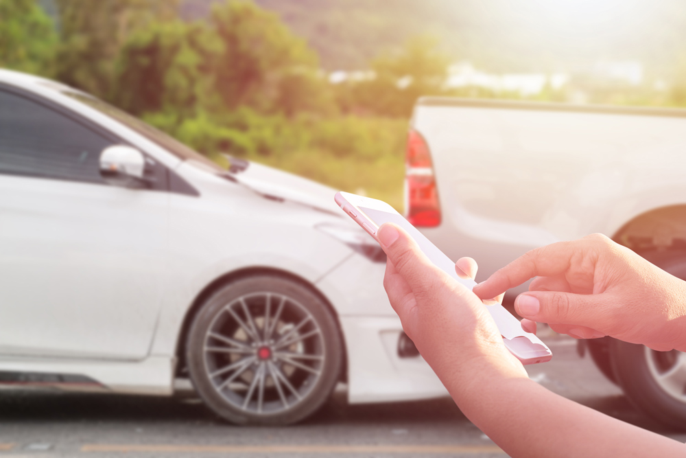 Two cars after colliding in a fender bender, one driver dialing on their cellphone